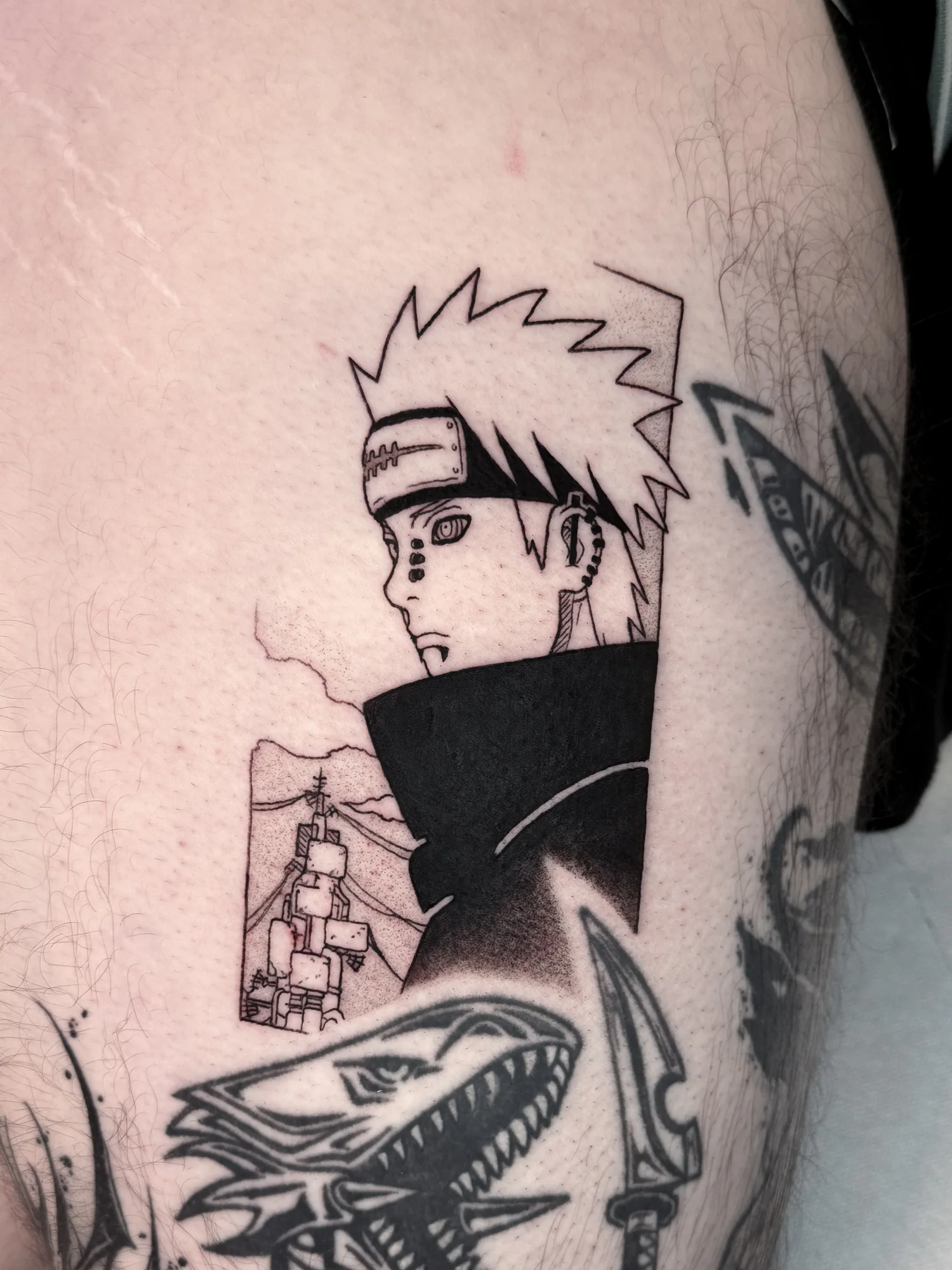 Tatouage blackwork de Pain, personnage de Naruto, inspiré d'une case manga et réalisé sur la cuisse.