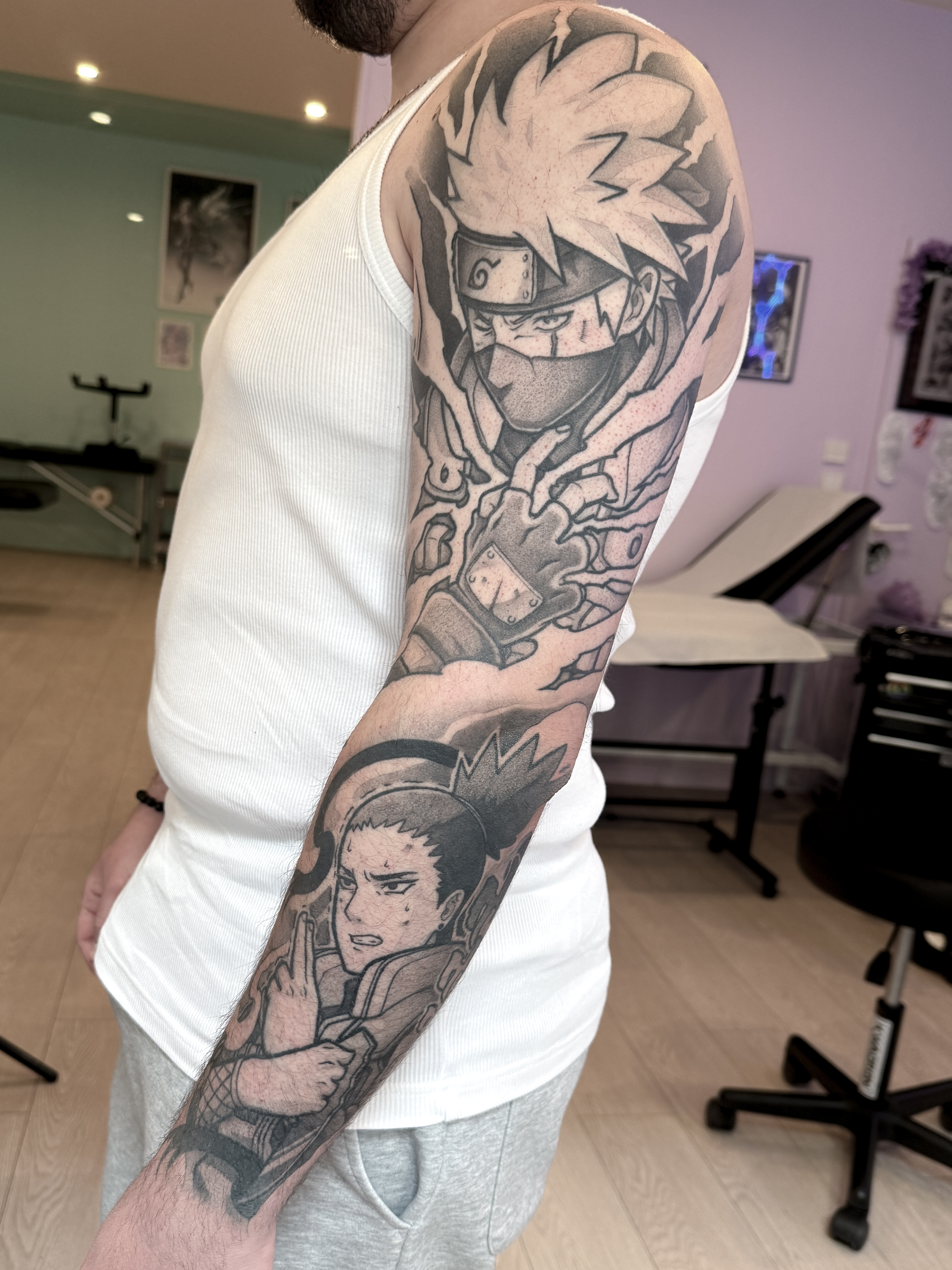 Sleeve blackwork cicatrisé Naruto et One Piece, avec Kakashi en haut et Shikamaru en bas, vu sur la face extérieure du bras.