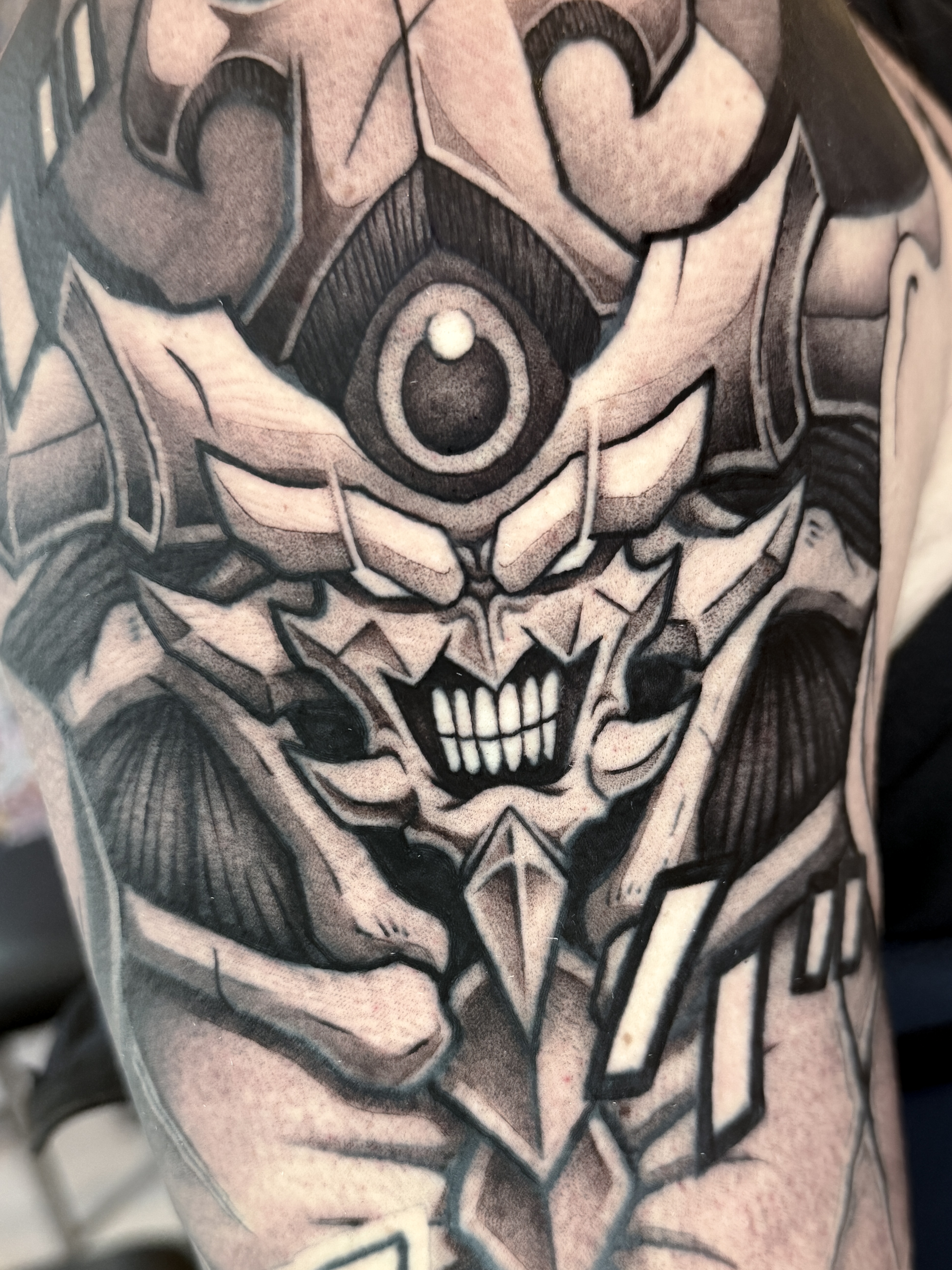 Gros plan blackwork sur le visage d'Obélisque le Tourmenteur de Yu-Gi-Oh!, intégré à un sleeve années 90.