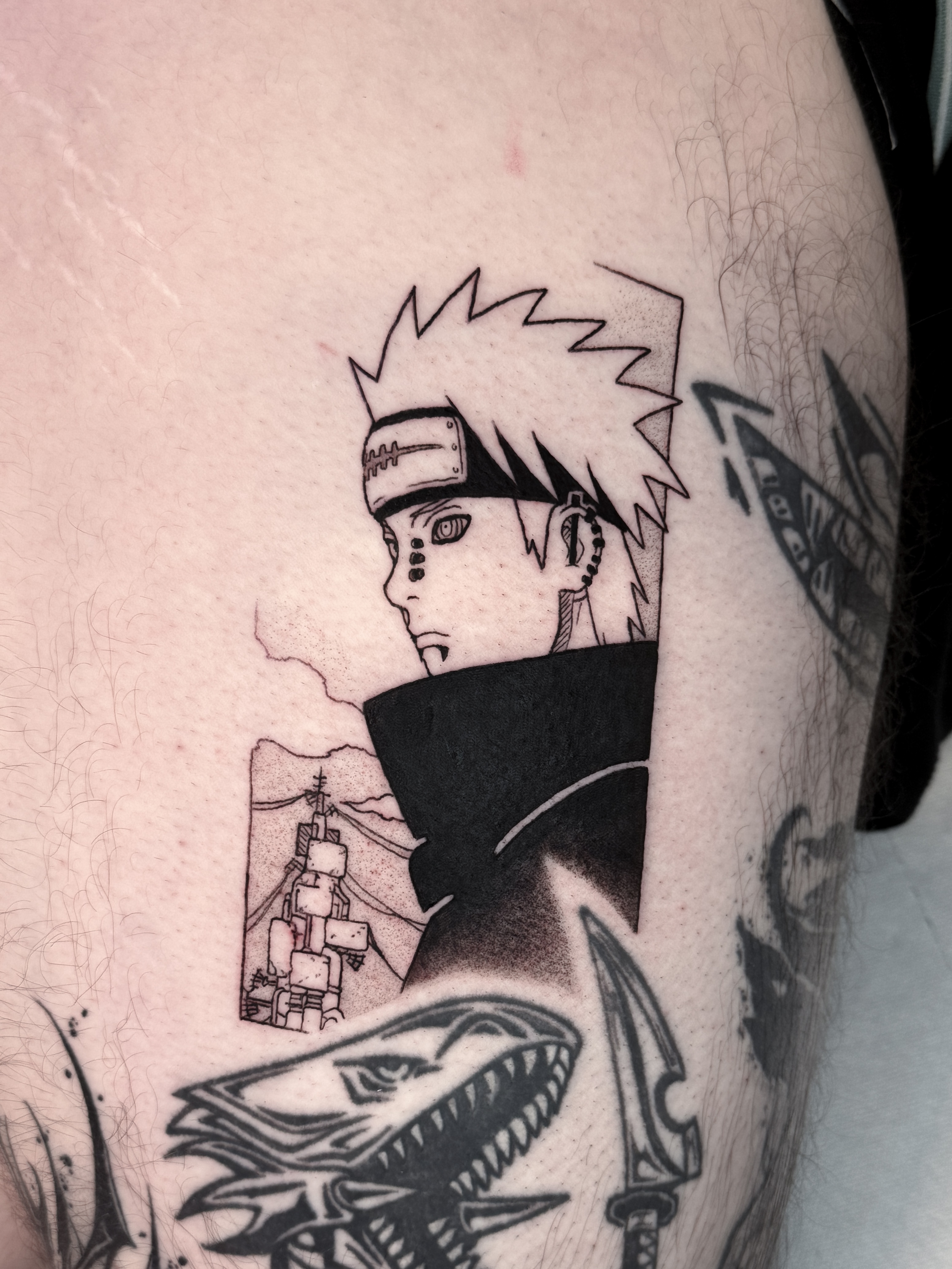 Tatouage blackwork de Pain, personnage de Naruto, inspiré d'une case manga et réalisé sur la cuisse.