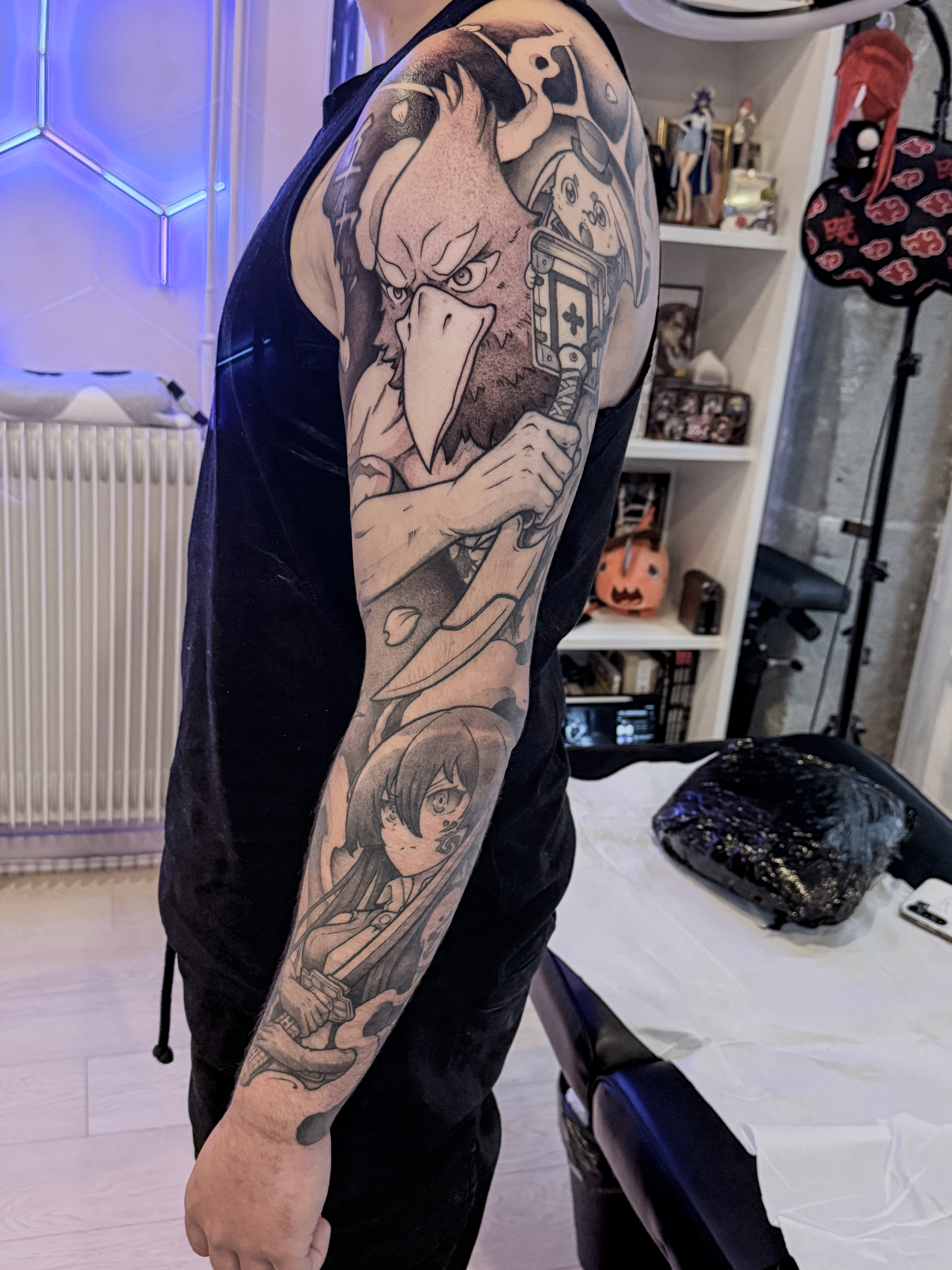 Sleeve manga et anime en blackwork avec Sunraku et Emul de Shangri-La Frontier sur le haut du bras, et Akame de Akame ga Kill! dans la partie basse.